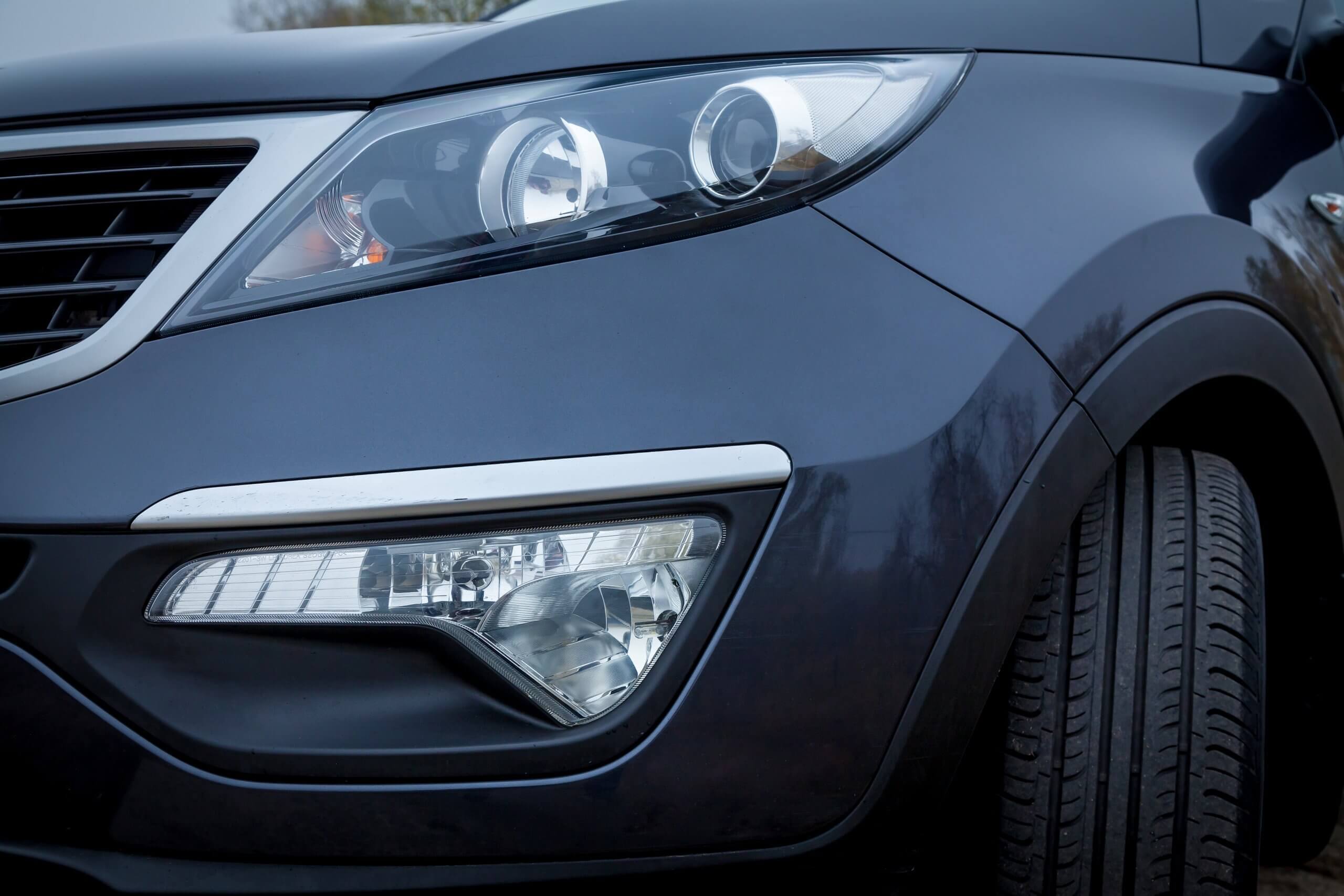 Nahaufnahme von Scheinwerfer und Kühlergrill eines dunkelblauen Autos mit modernem Design, das trotz Versicherungsproblemen auffällt